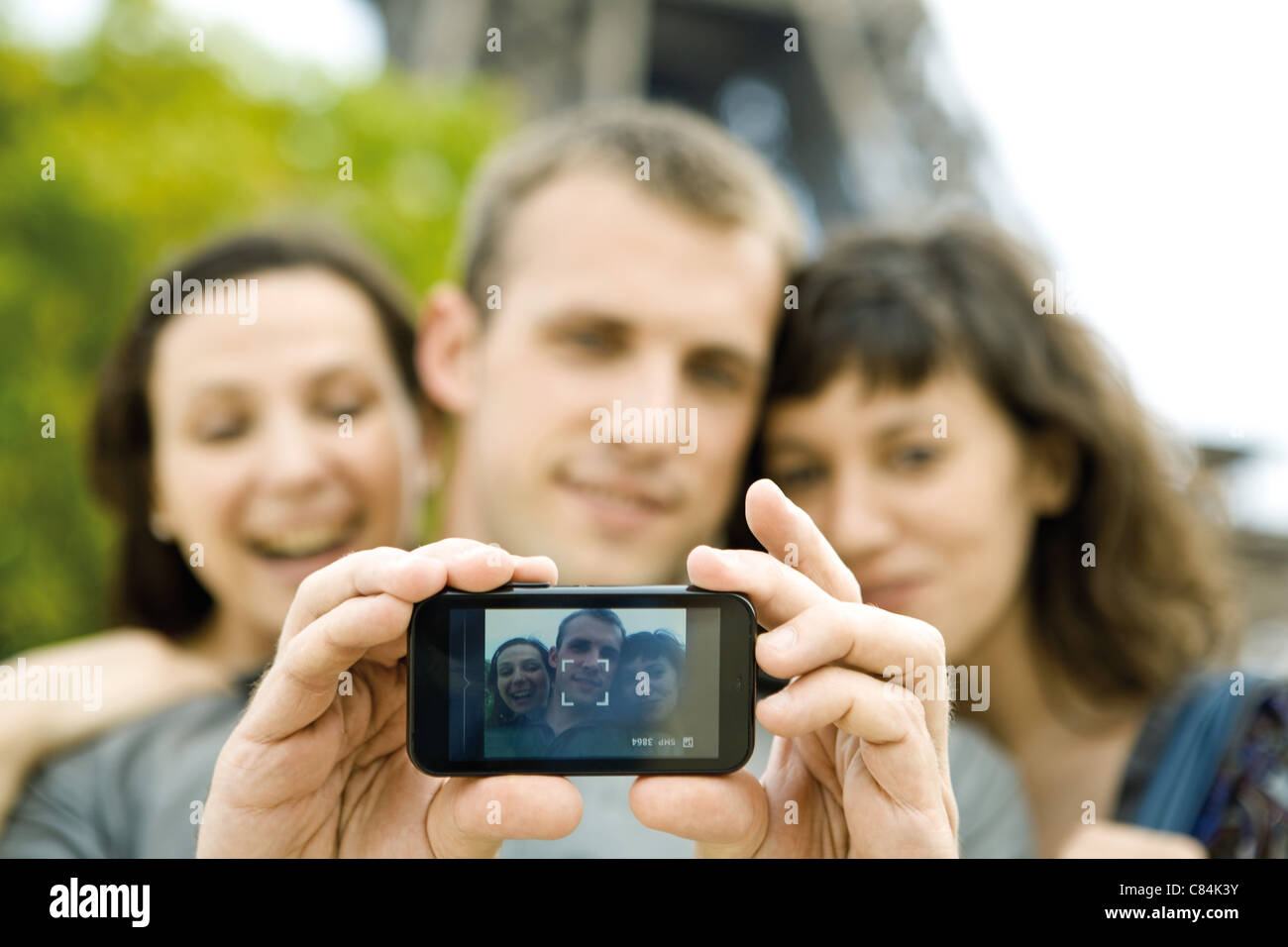 L'homme lui-même photographier avec deux amies using cell phone Banque D'Images