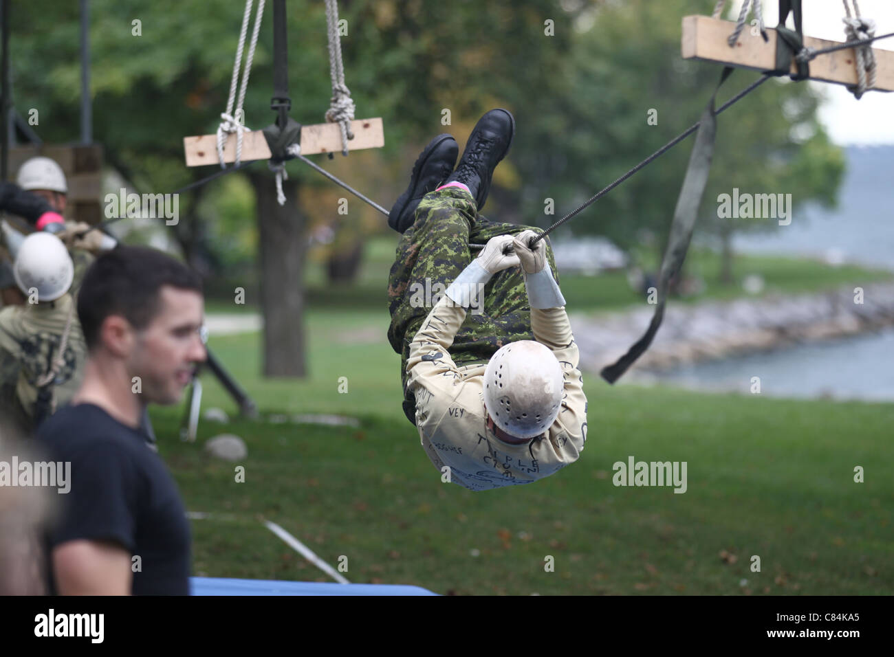 L'homme sur manual zip line lors d'une course d'obstacles militaires Banque D'Images