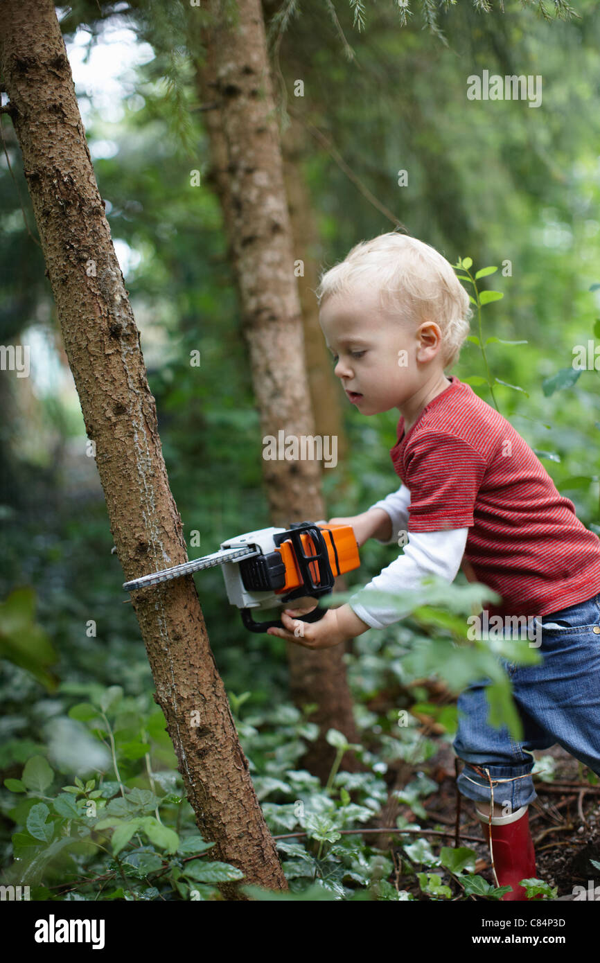 Bébé garçon à l'aide de tronçonneuse jouet en plein air Banque D'Images