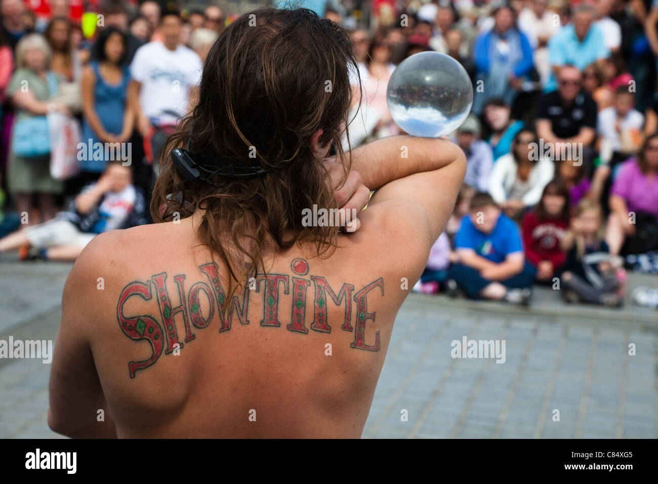 Artiste de rue à l'Edinburgh Fringe Festival avec un tatouage de 'Showtime' sur le dos, jouant à un public sur la Butte Banque D'Images Artiste de rue à l'Edinburgh Fringe Festival avec un tatouage de 'Showtime' sur le dos, jouant à un public sur la Butte Banque D'Images