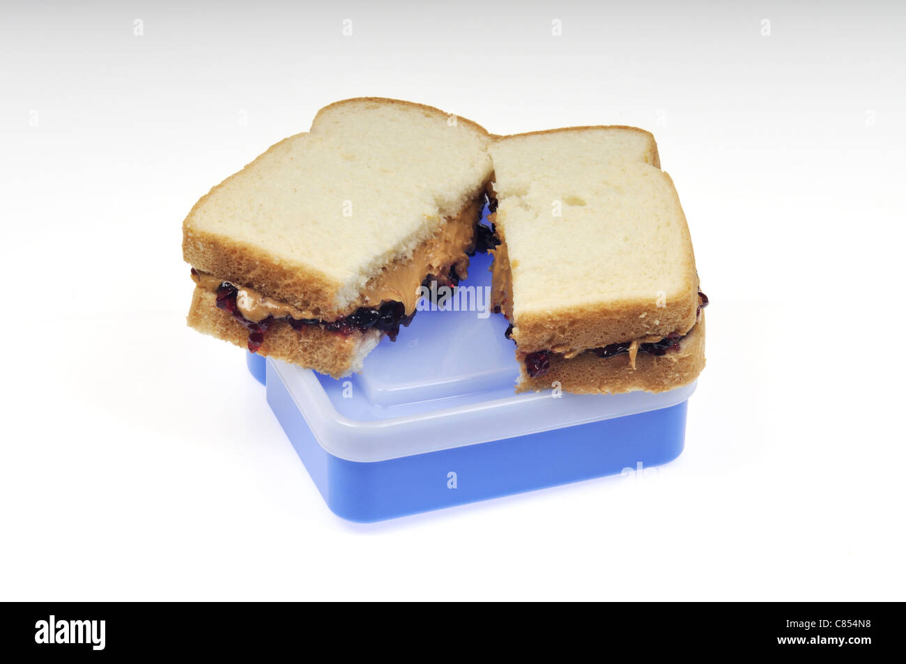 Peanut butter and jelly sandwich sur pain blanc sur le dessus de la boîte en plastique contenant le déjeuner. Banque D'Images