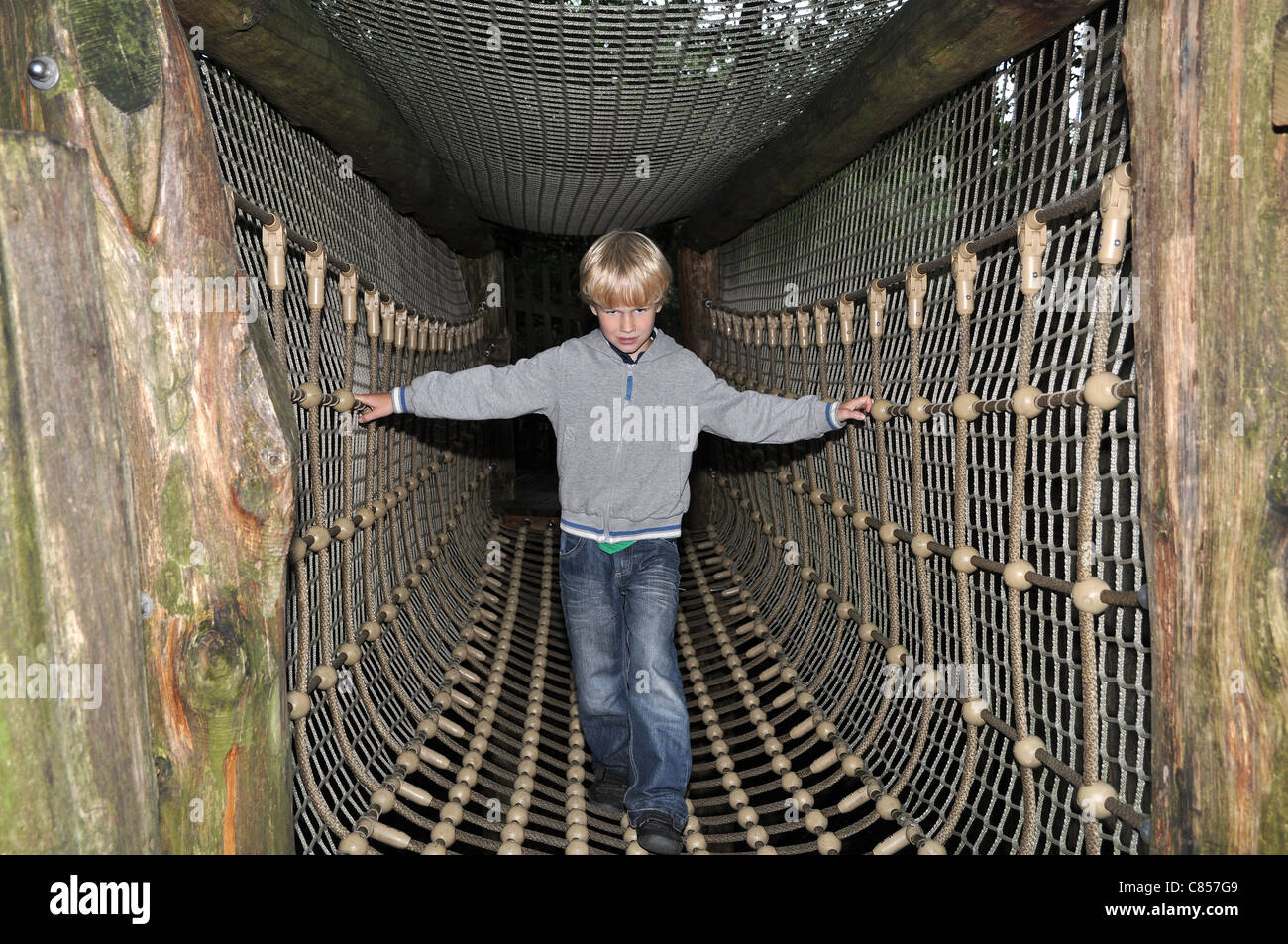 Jeune garçon traverser un pont de corde suspendu Banque D'Images