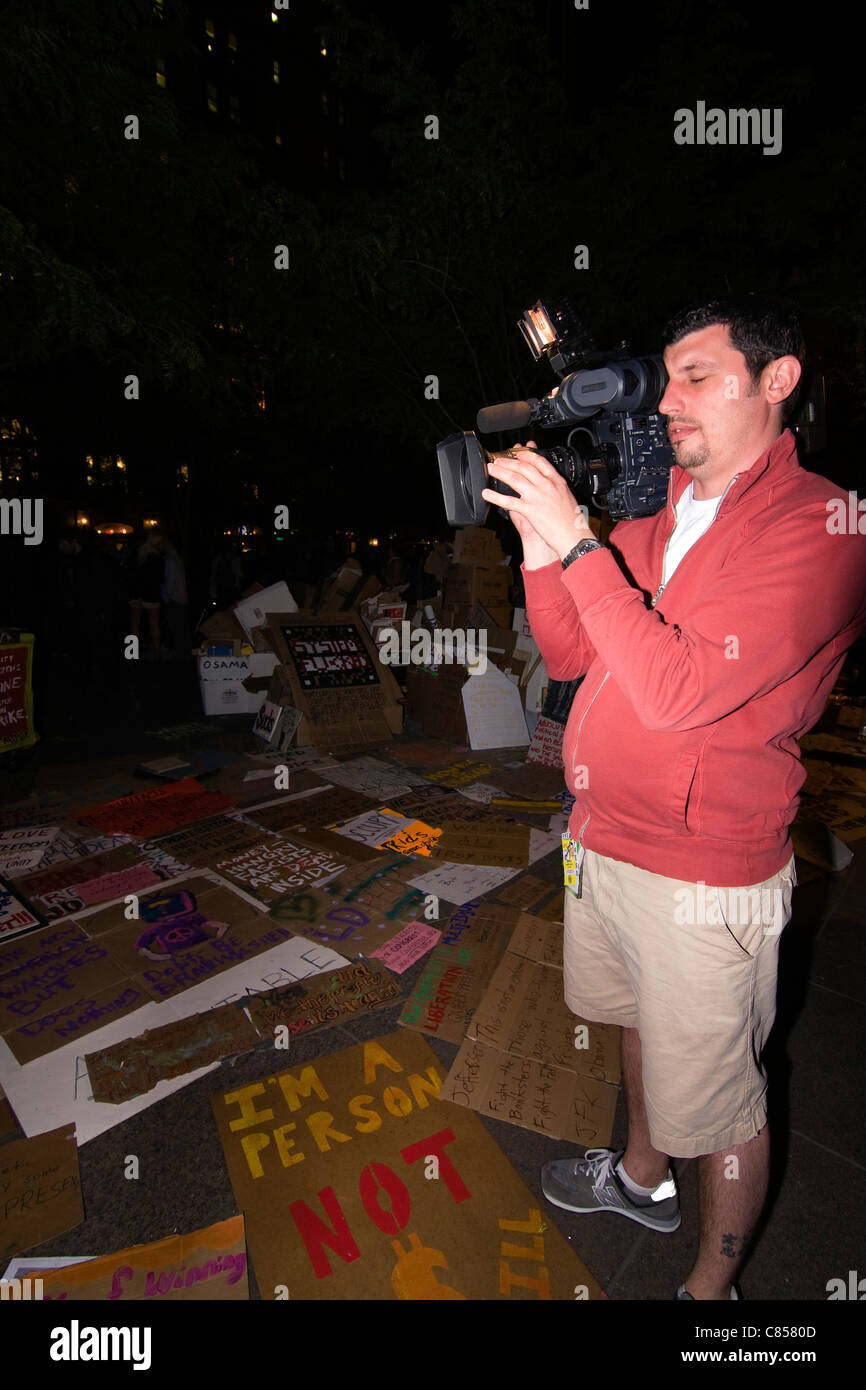 Caméraman de la télévision des pancartes lors de l'enregistrement de nuit à Zuccotti Park pendant les "Occupy Wall Street" à NEW YORK Banque D'Images