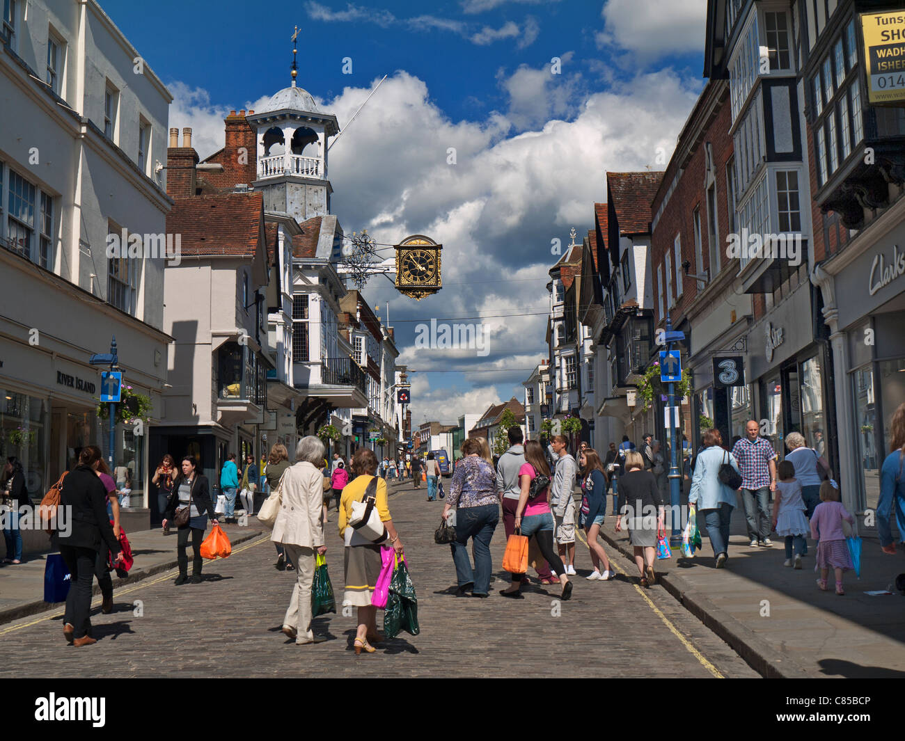 GUILDFORD Shoppers foules occupées dans Guildford historique et pavée circulation libre High Street avec horloge célèbre, profitant du soleil printanier Guildford Surrey Royaume-Uni Banque D'Images