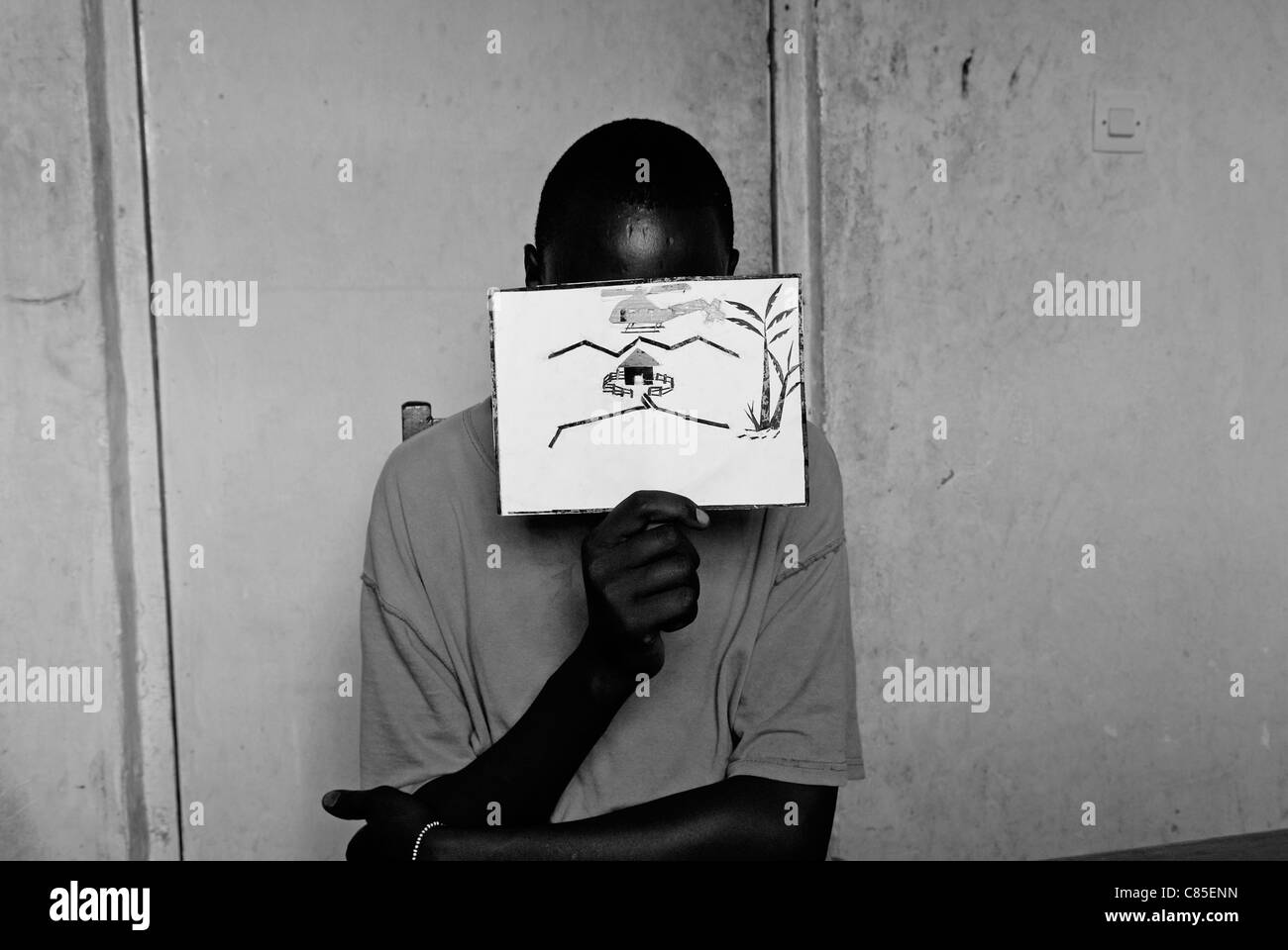 Un ancien enfant soldat tient un dessin illustrant les atrocités de guerre du Centre pour le transit et l'orientation pour les anciens enfants soldats exploités par le CAJED, une ONG congolaise soutenue par l'UNICEF qui travaille avec des enfants et des jeunes défavorisés dans la ville de Goma. Province du Nord-Kivu RD Congo Afrique Banque D'Images