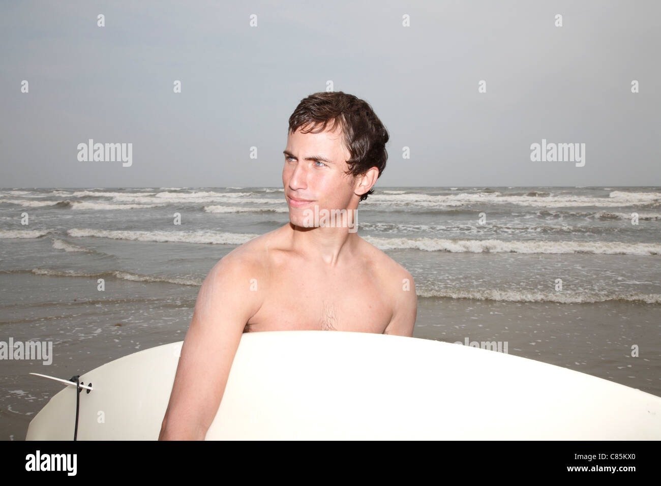 Man Holding Surfboard, Galveston, Galveston Island, Comté de Galveston, Texas, États-Unis Banque D'Images