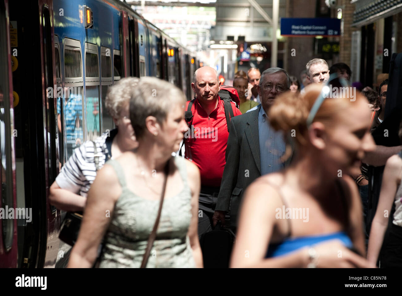 Les passagers de descendre d'un train à une gare occupée en Angleterre. Banque D'Images