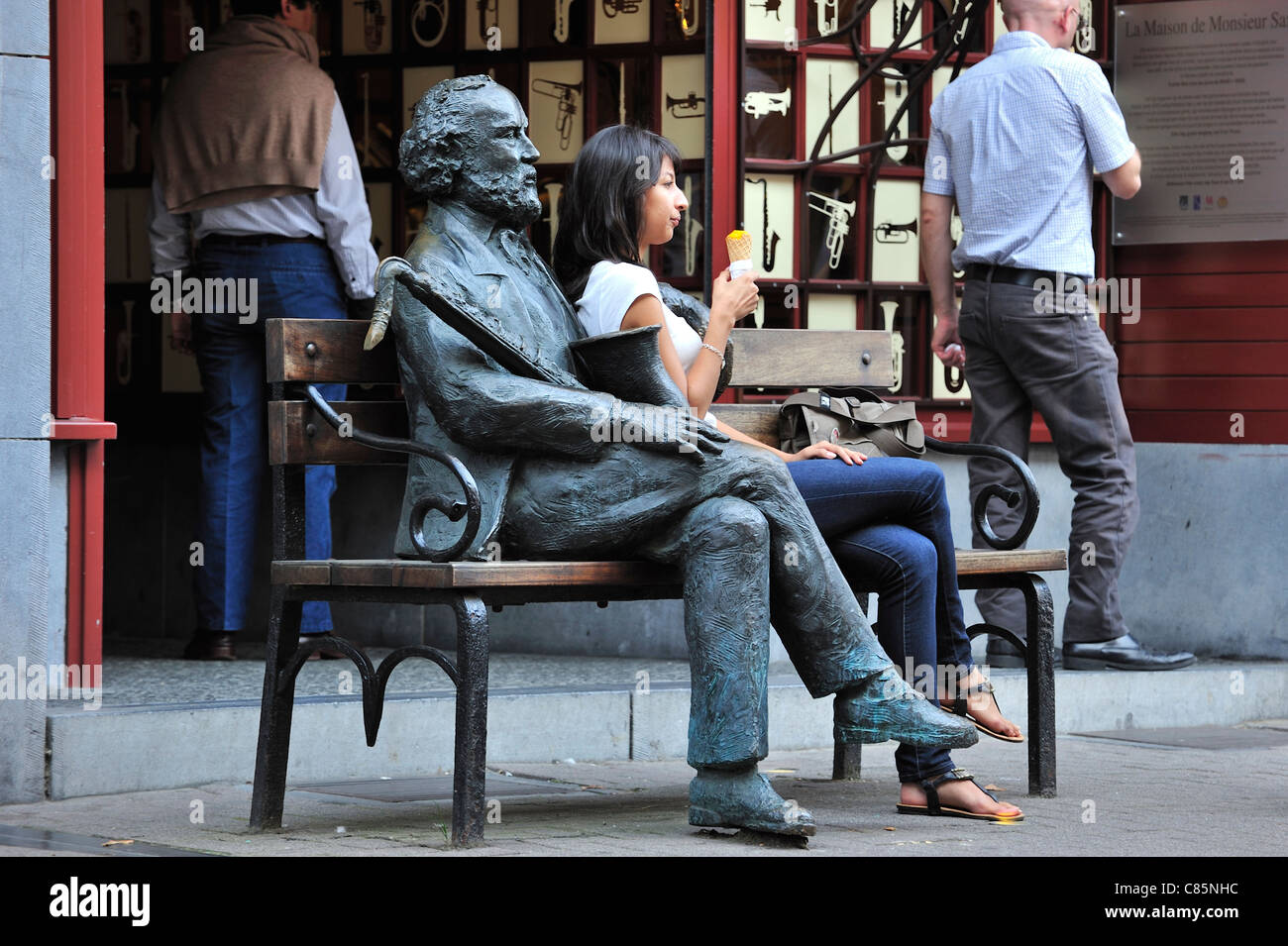 Woman posing près de statue d'Adolphe Sax, concepteur d'instruments de musique belge et de l'inventeur du saxophone, Dinant, Belgique Banque D'Images
