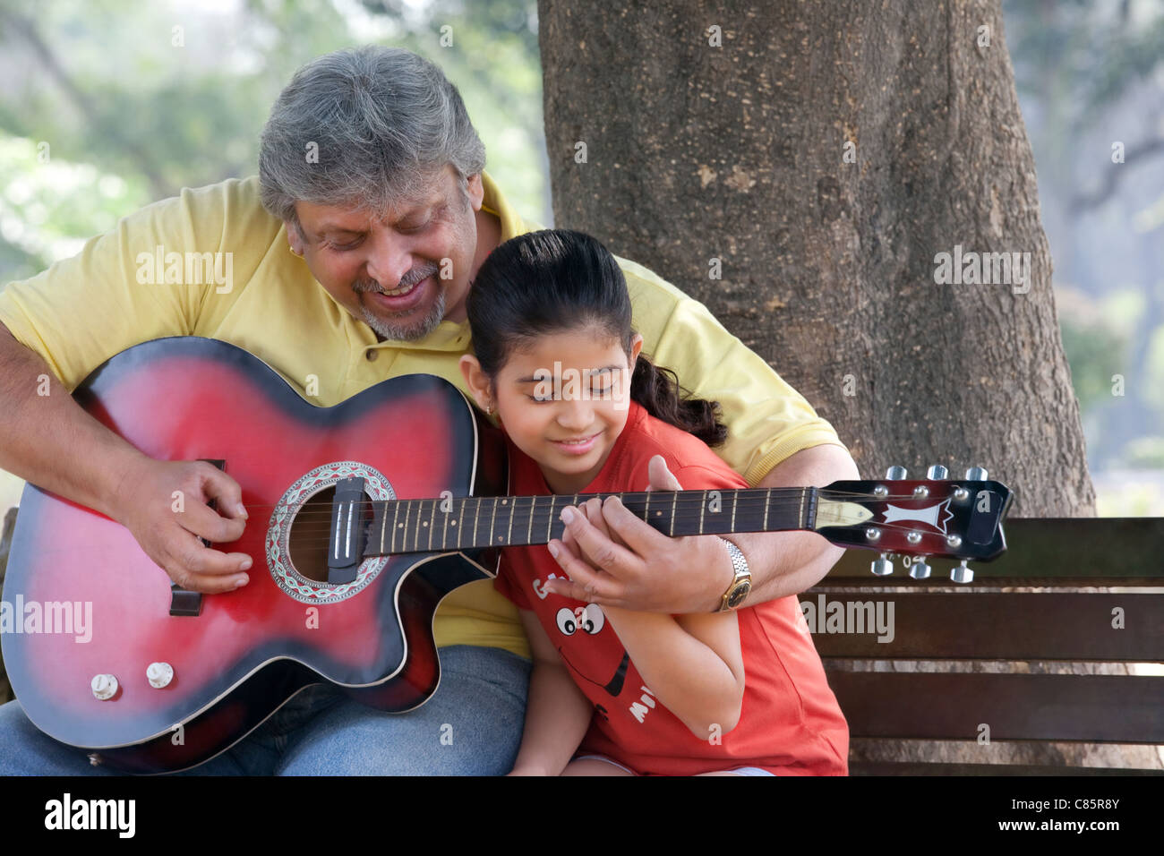 L'enseignement de son grand-père sa petite-fille à jouer de la guitare Banque D'Images