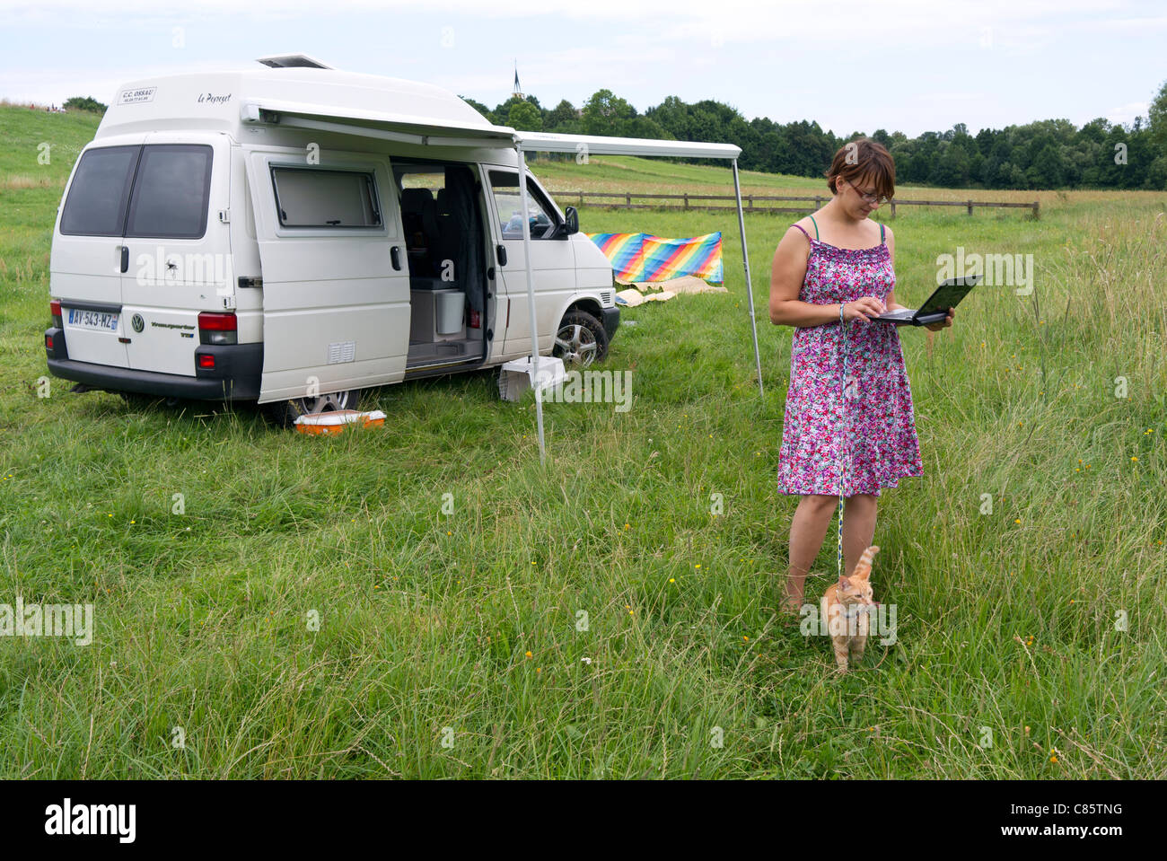 Pologne, Parc National de la rivière Biebrza, VW T4 camping-transporteur, dame avec un chat en laisse à l'aide de GSM sans fil à internet Banque D'Images