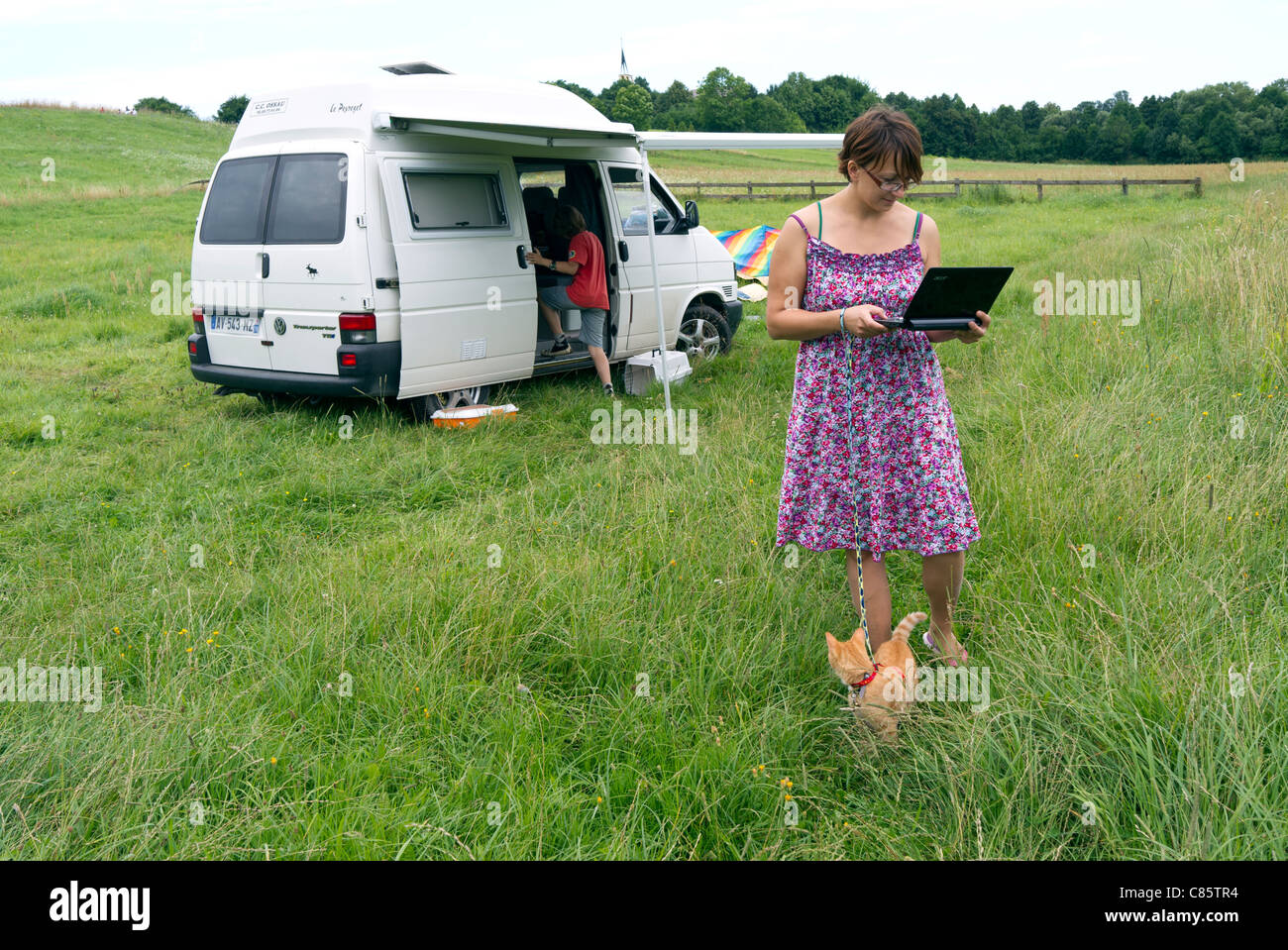 Pologne, Parc National de la rivière Biebrza, VW T4 camping-transporteur, dame avec un chat en laisse à l'aide de GSM sans fil à internet Banque D'Images