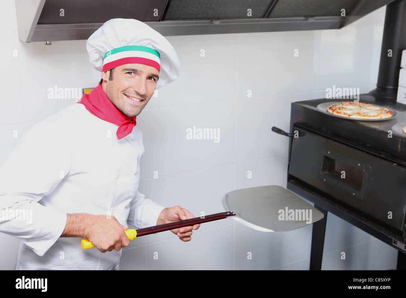 Cuisinier pizza en face d'un four Banque D'Images