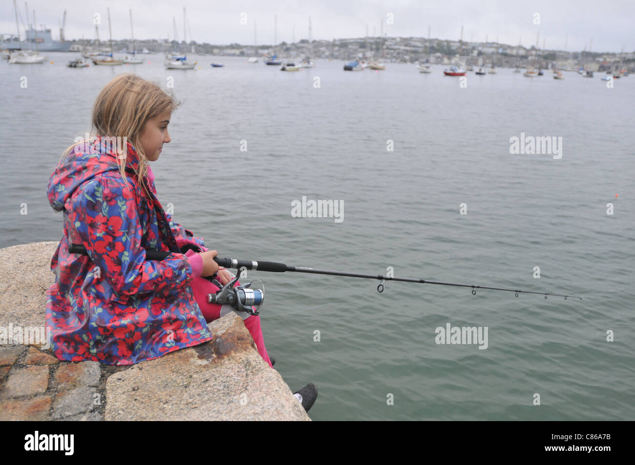 Une fillette de 8 ans la pêche dans le rinçage, Cornwall Falmouth avec en arrière-plan. Banque D'Images