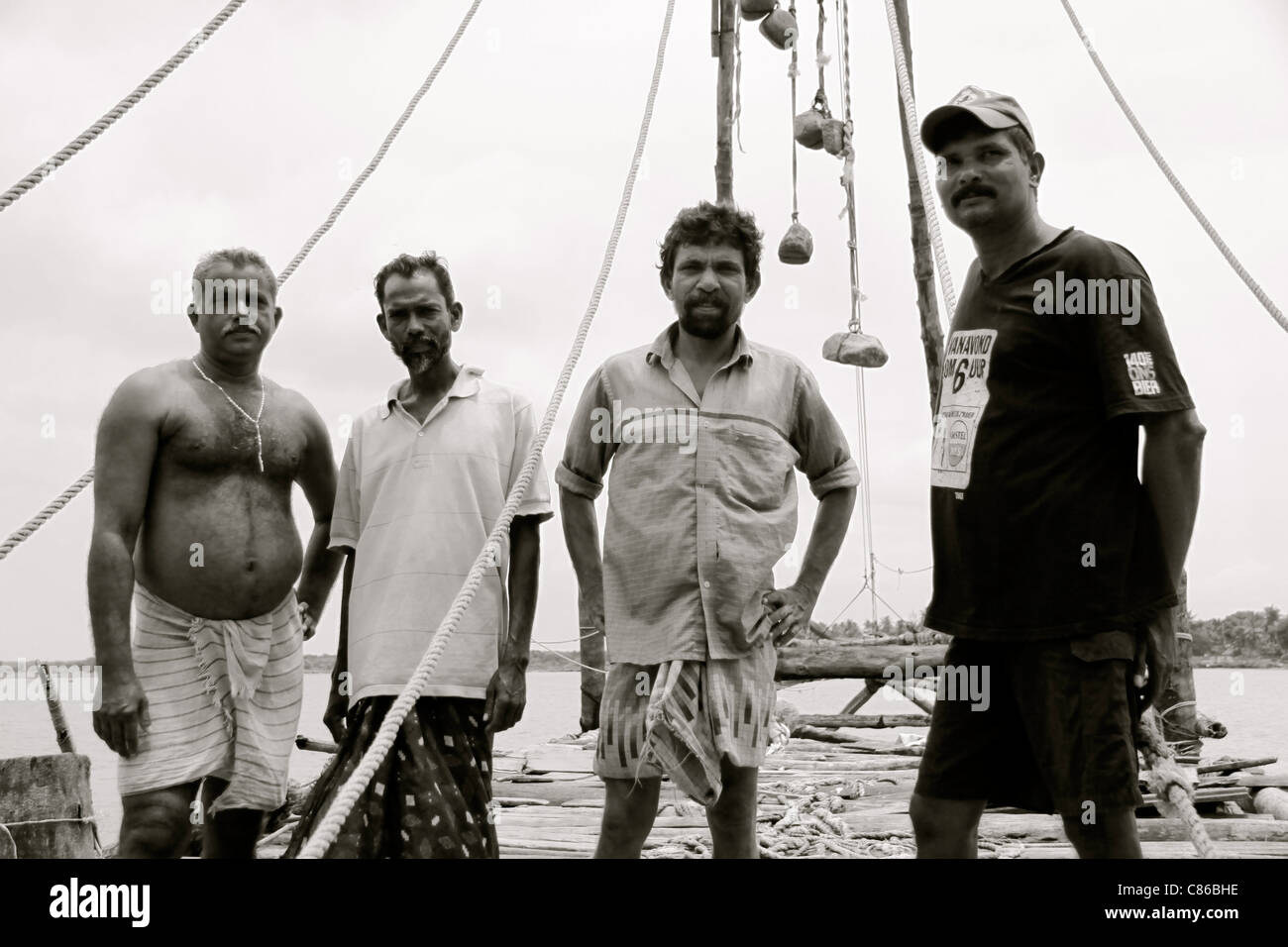 Quatre pêcheurs avec leurs filets de pêche chinois à Kochi, Kerala, Inde Banque D'Images