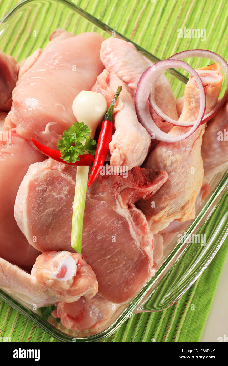 Le poulet cru et la viande de porc dans un plat en verre Banque D'Images