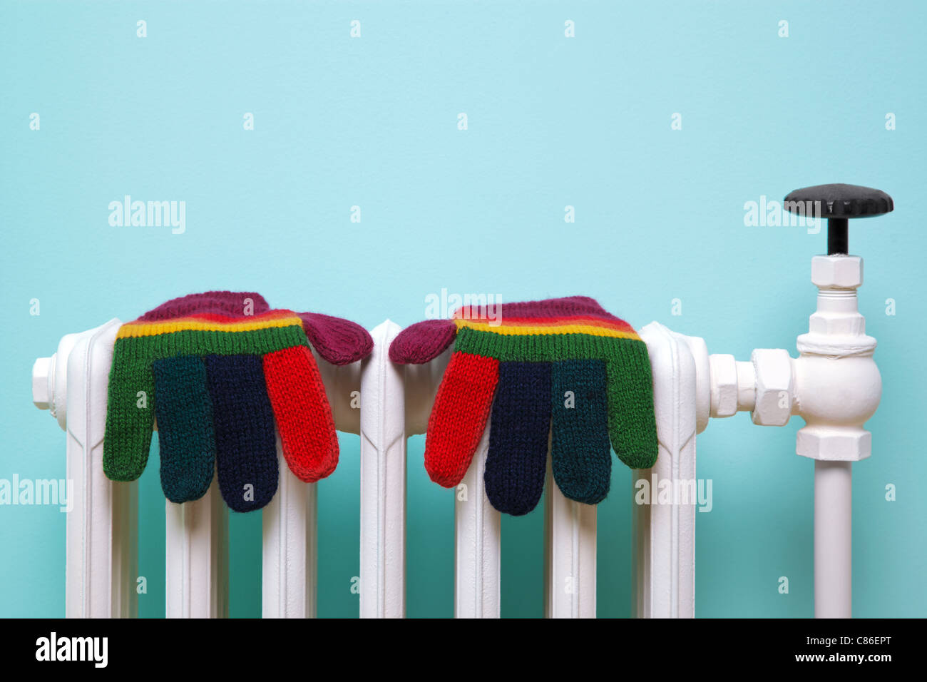 Photo d'une paire de gants de laine tricotés main séchage à rayures sur un vieux radiateur en fonte traditionnelle. Banque D'Images