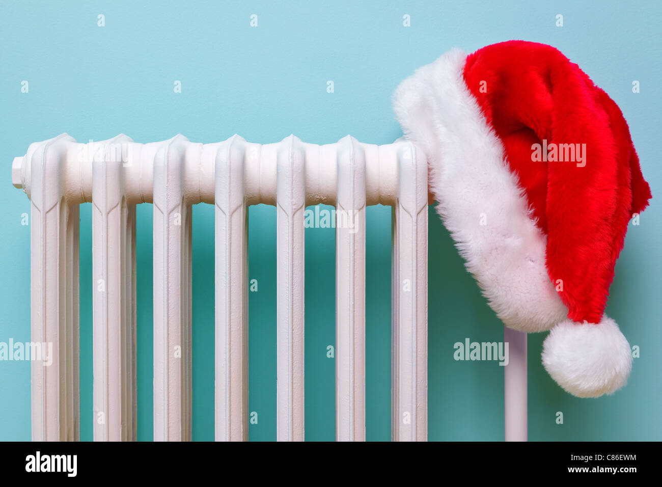 Photo d'un Père Noël rouge et blanc hat hanging sur un vieux radiateur en fonte traditionnelle. Banque D'Images