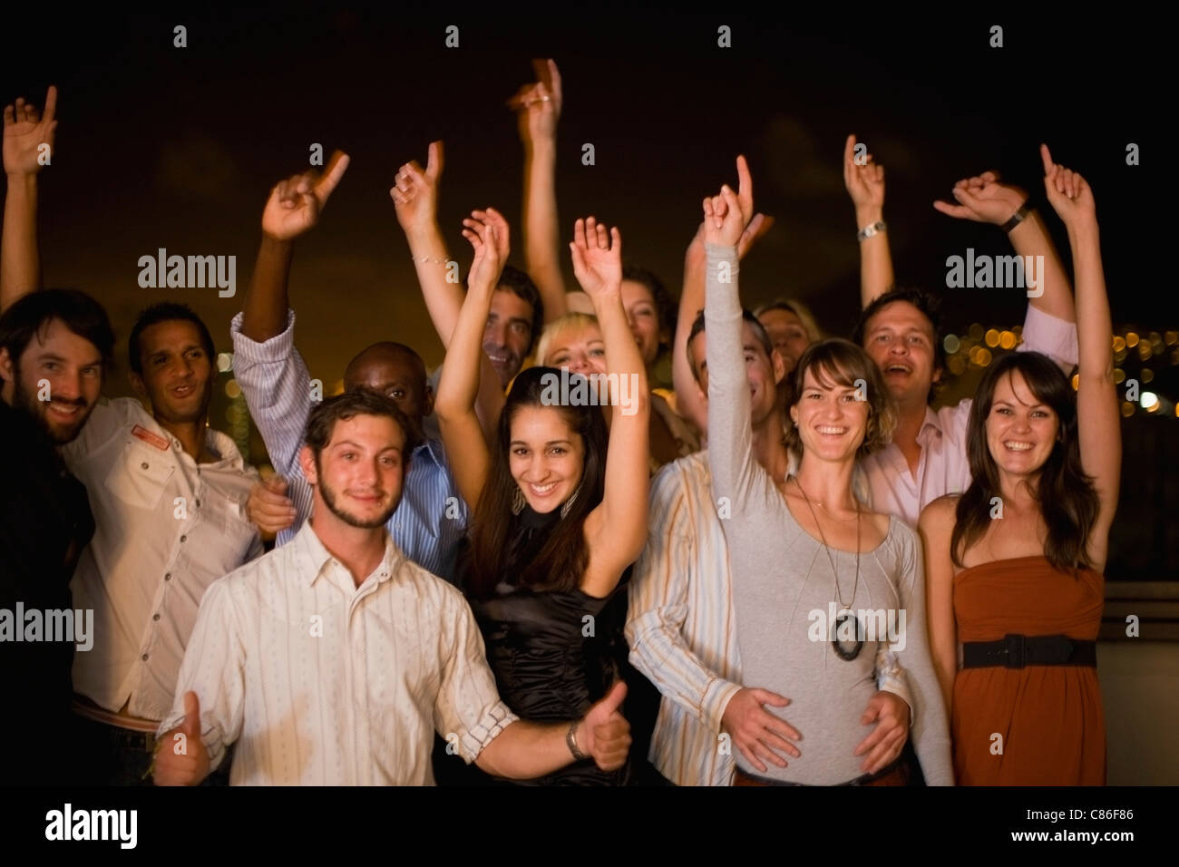 Les gens cheering at party at night Banque D'Images
