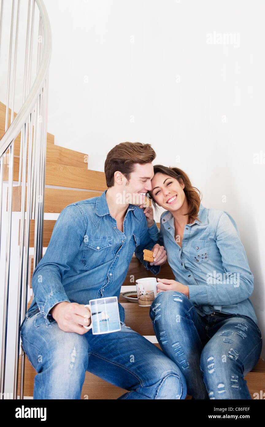 Couple drinking coffee on stairs Banque D'Images