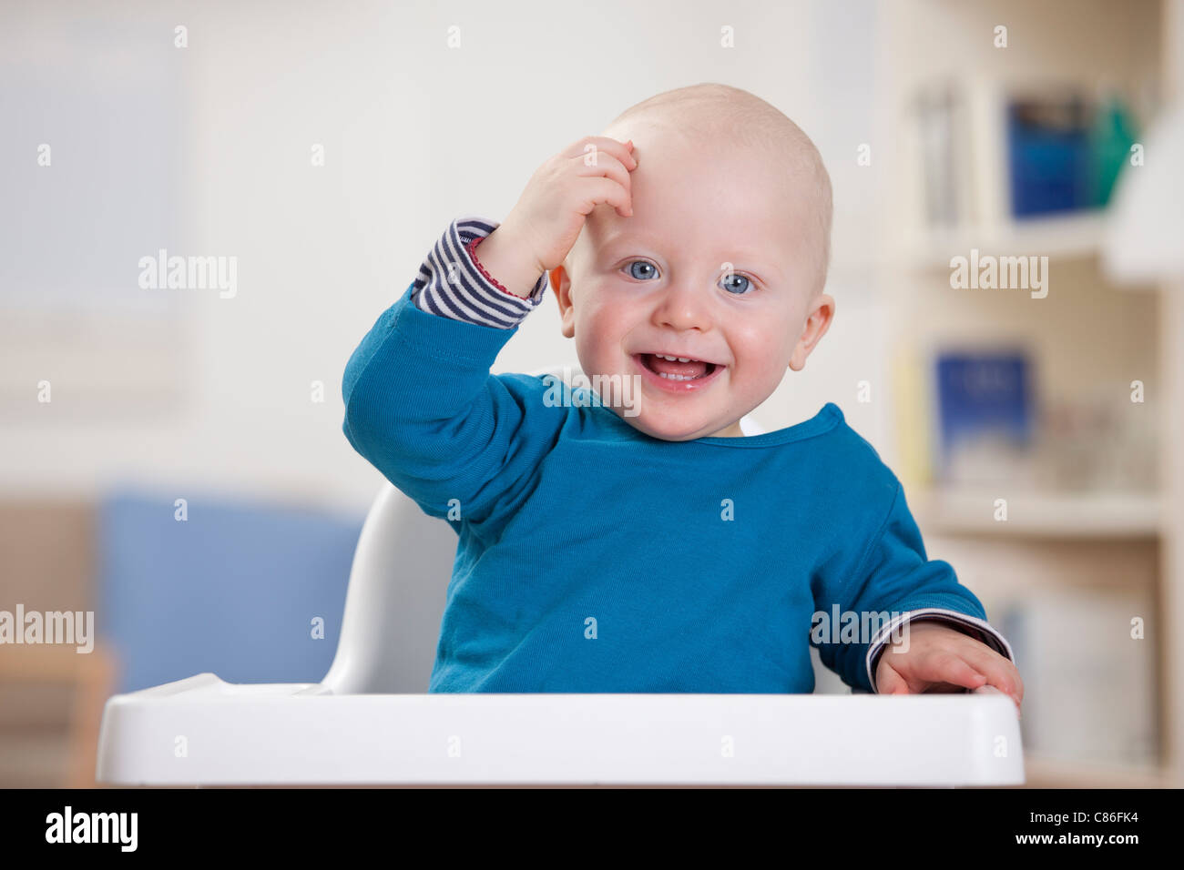 Smiling baby boy sitting in chaise haute Banque D'Images