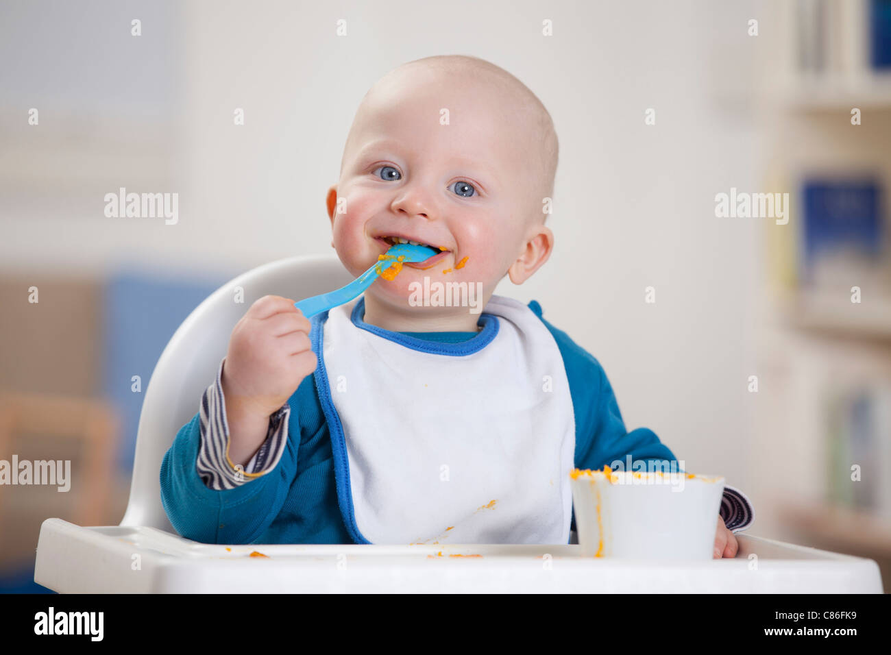 Smiling baby boy eating dans une chaise haute Banque D'Images