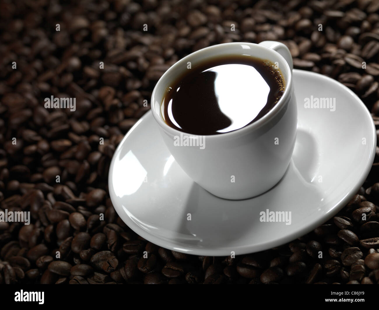 Tasse de café avec une soucoupe sur fond de grain de café Banque D'Images