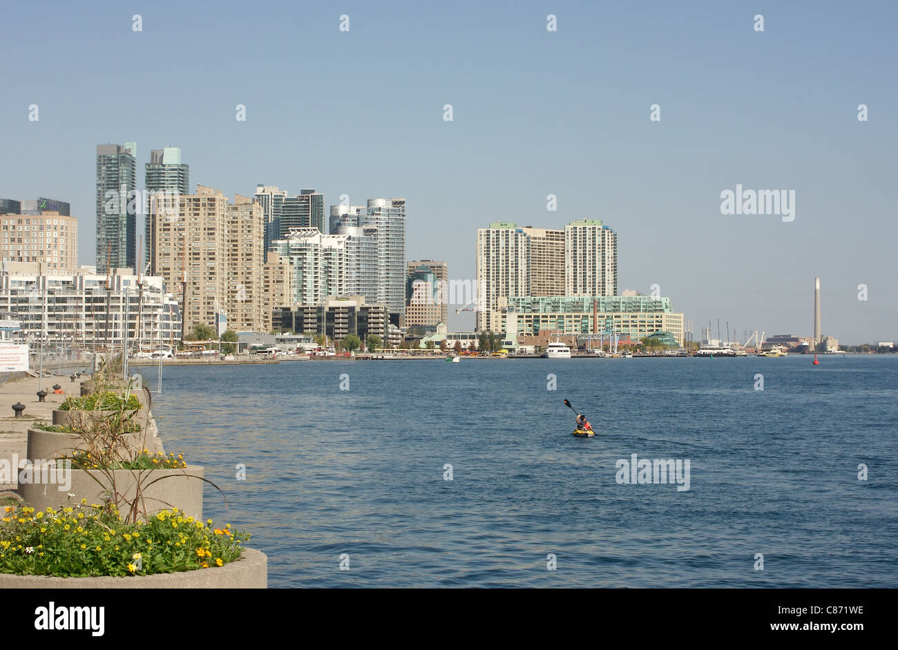 Man in a kayak pagaies le long de la façade portuaire de Toronto Skyline moderne de Toronto dans l'arrière-plan Banque D'Images