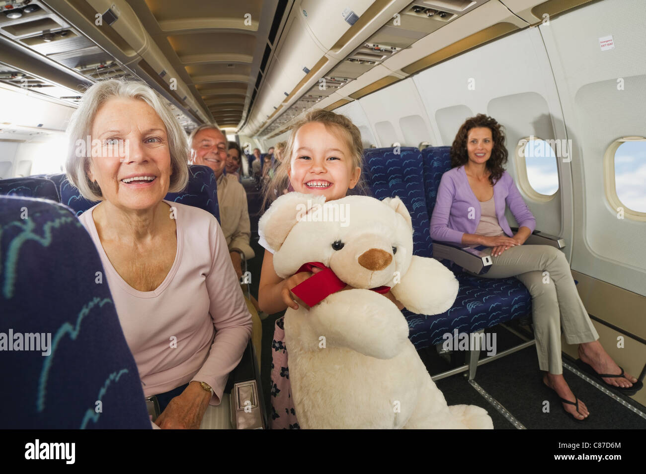 Allemagne, Munich, Bavaria, Girl holding teddy bear en avion en classe économique Banque D'Images