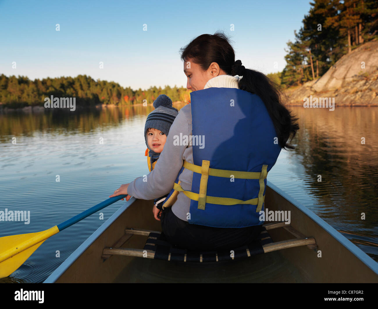 Femme dans un canoë avec un enfant. Coucher du soleil automne nature paysage. Pagayer à Killarney Provincial Park, Ontario, Canada. Banque D'Images