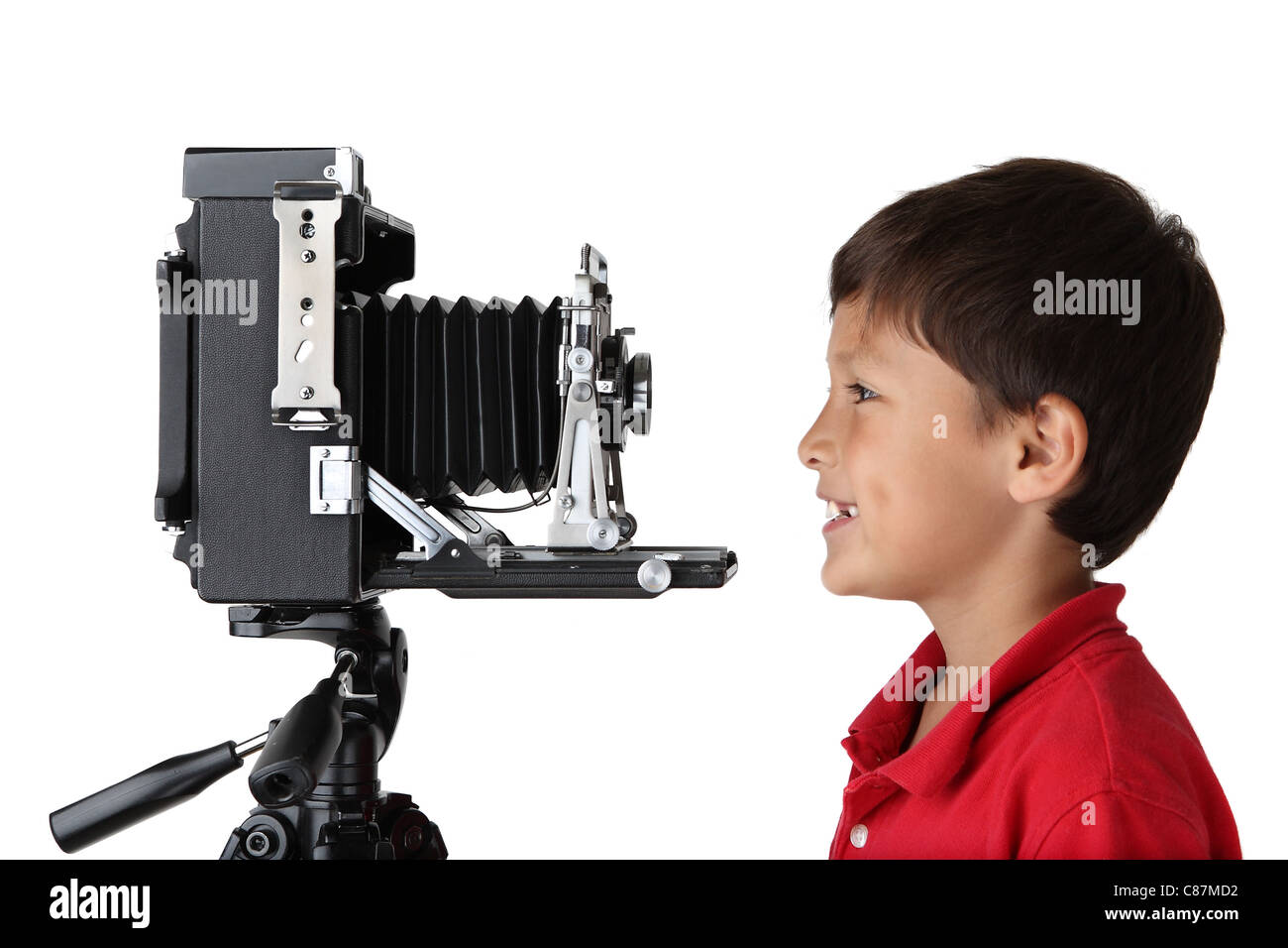Happy smiling boy en chemise rouge à la presse à de vieux appareil photo sur fond blanc Banque D'Images