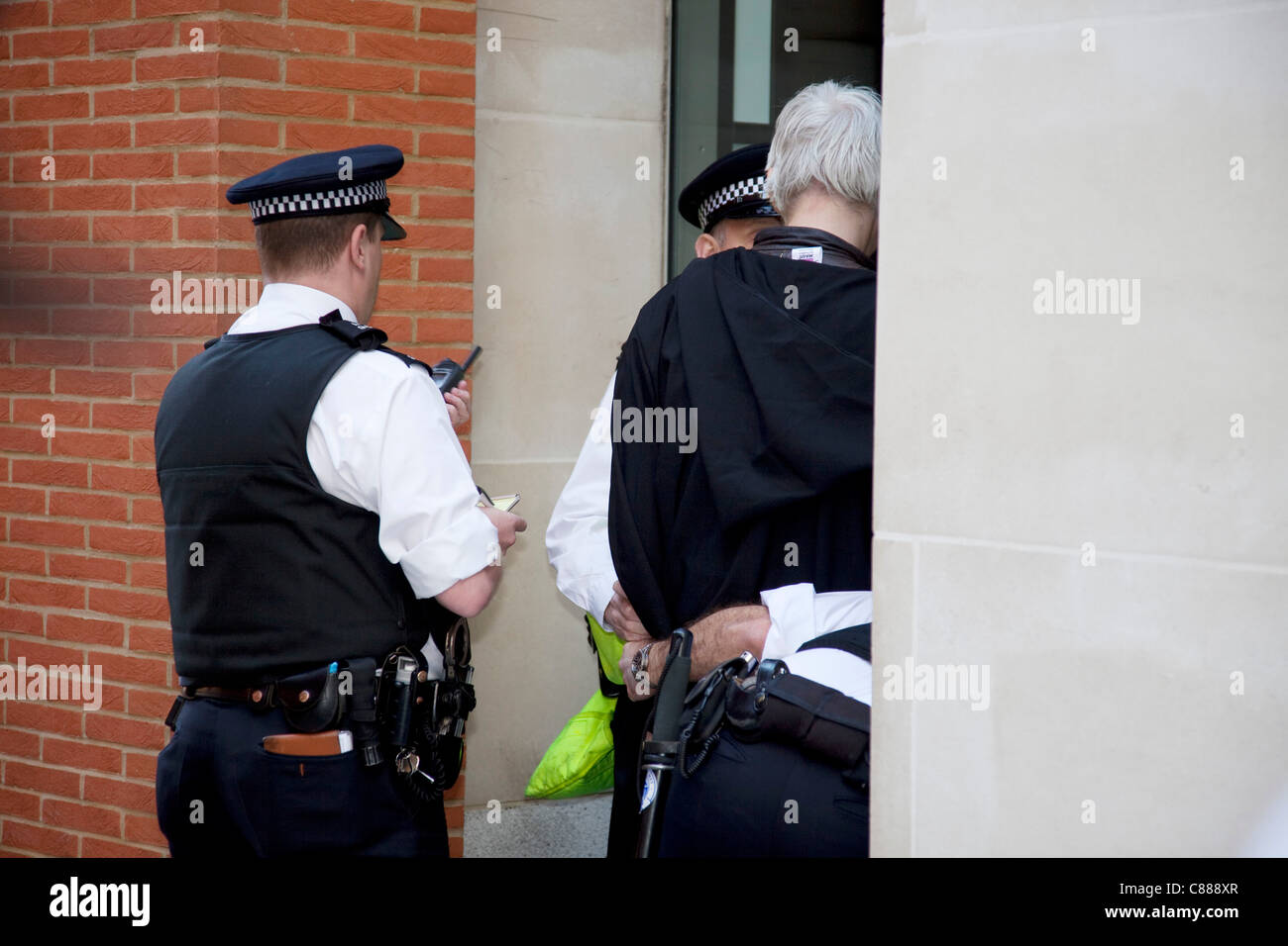 Julian Assange de WikiLeaks à la manifestation Occupy London 15 octobre 2011. Vu ici, il essaie de passer à travers les lignes de police portant une cape noire, le capot et le masque. Il a immédiatement demandé de retirer le masque où il a été traîné dans sur, interrogé et relâché. Banque D'Images