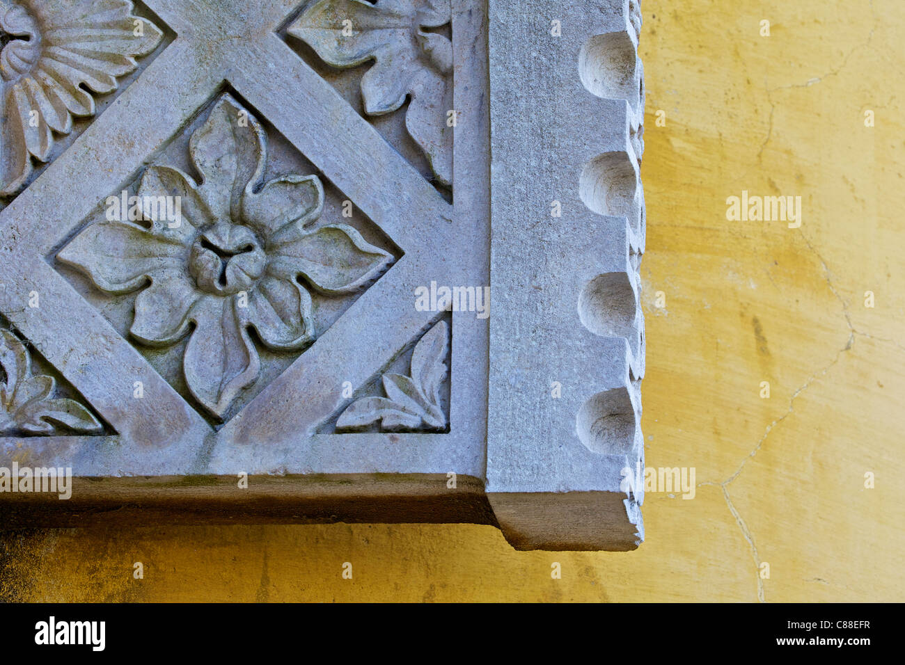 Conception d'ornements en pierre sculptée sur un mur de plâtre jaune Banque D'Images