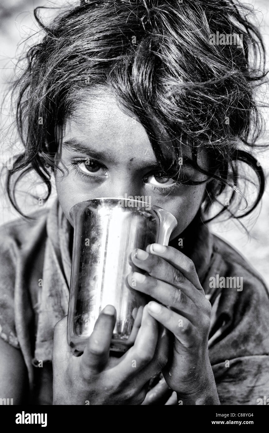 Les jeunes Indiens de castes inférieures pauvres street girl boire du lait. L'Inde. Monochrome Banque D'Images