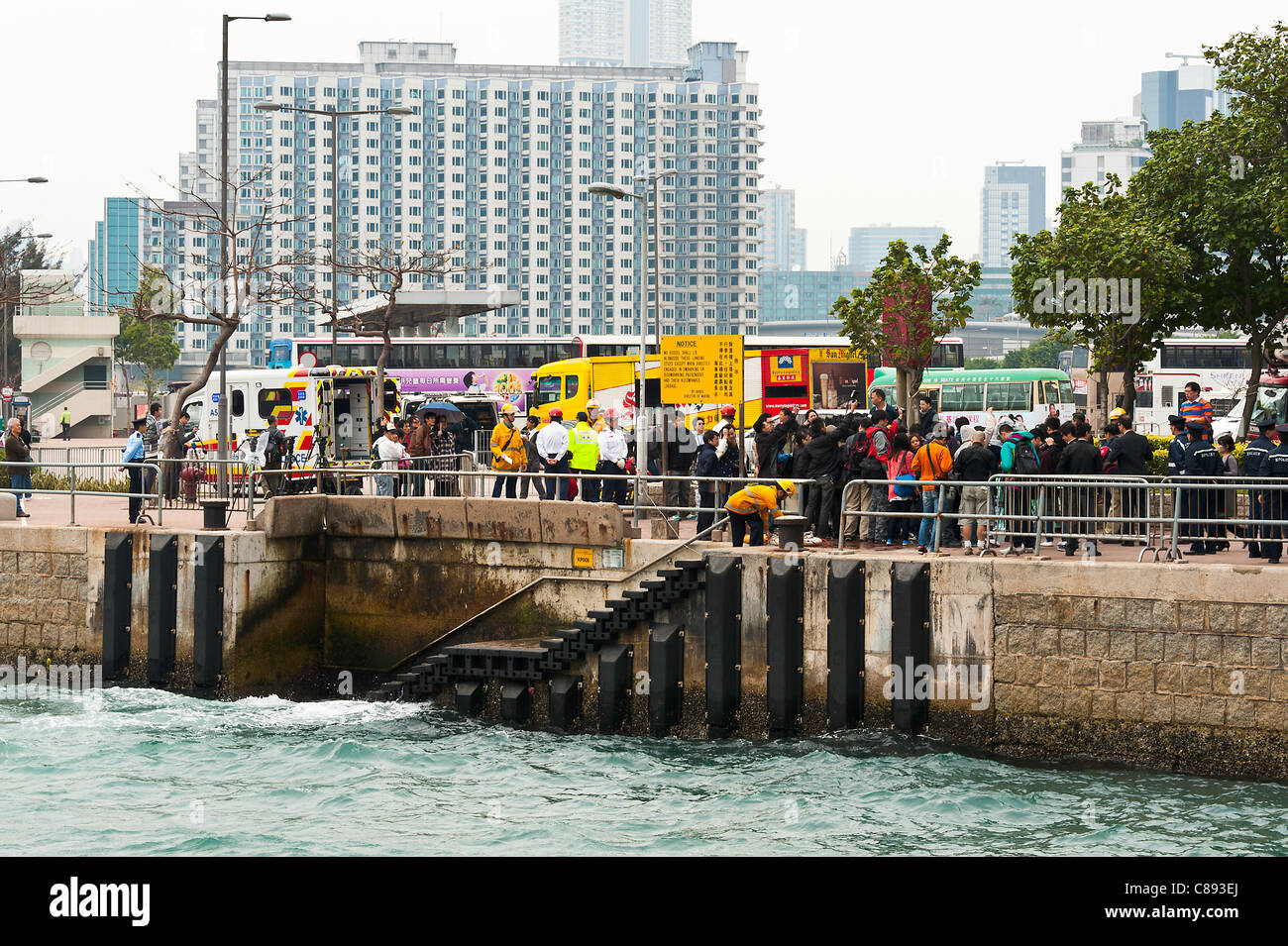 Les services de secours avec foule de visiteurs aider personne handicapée sur ponton à Kowloon Hong Kong Chine Asie Banque D'Images
