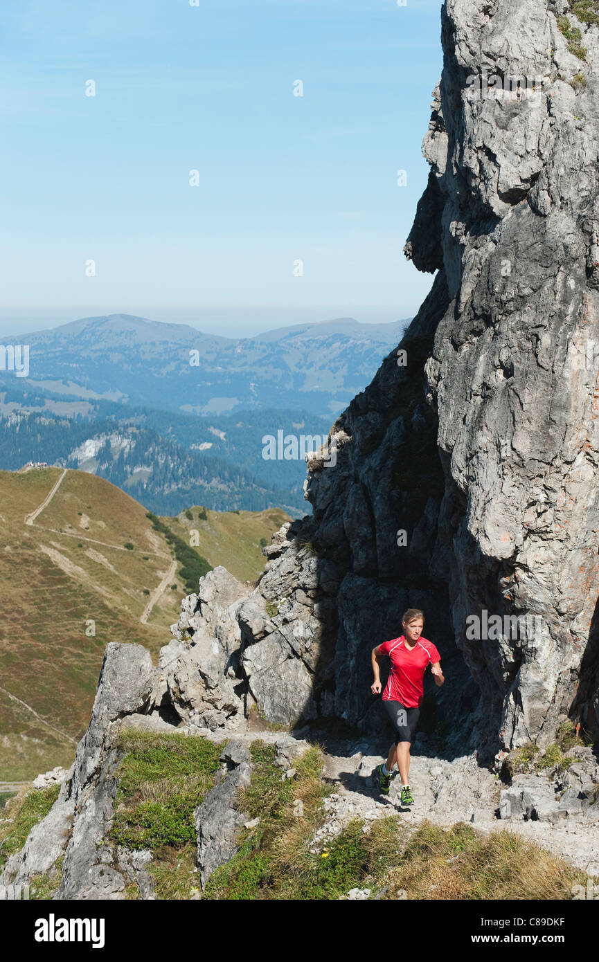 L'Autriche, Kleinwalsertal, jeune femme tournant sur sentier de montagne à proximité de rochers Banque D'Images