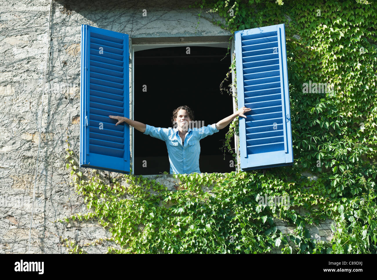 Italie, Toscane, Young man leaning on fenêtre avec volets roulants Banque D'Images