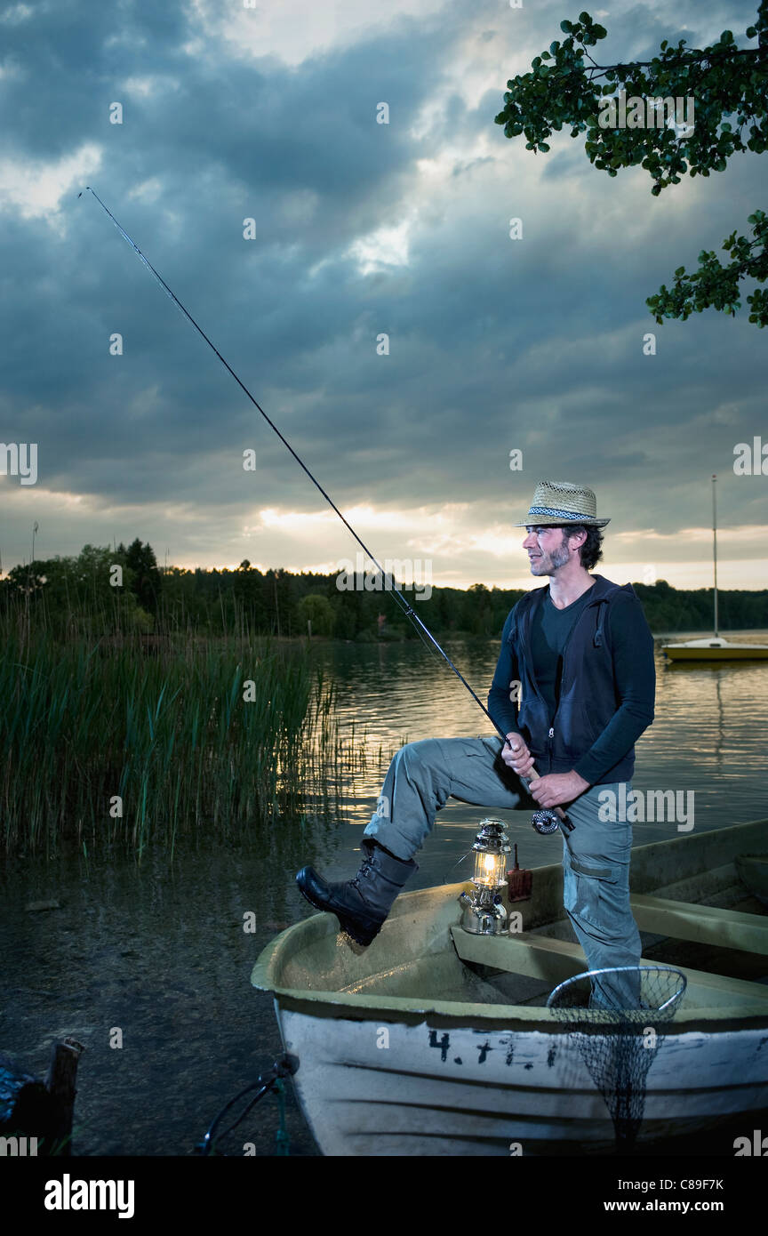 Allemagne, Bavière, Woerthsee, Man with lantern pêche en bateau au crépuscule Banque D'Images