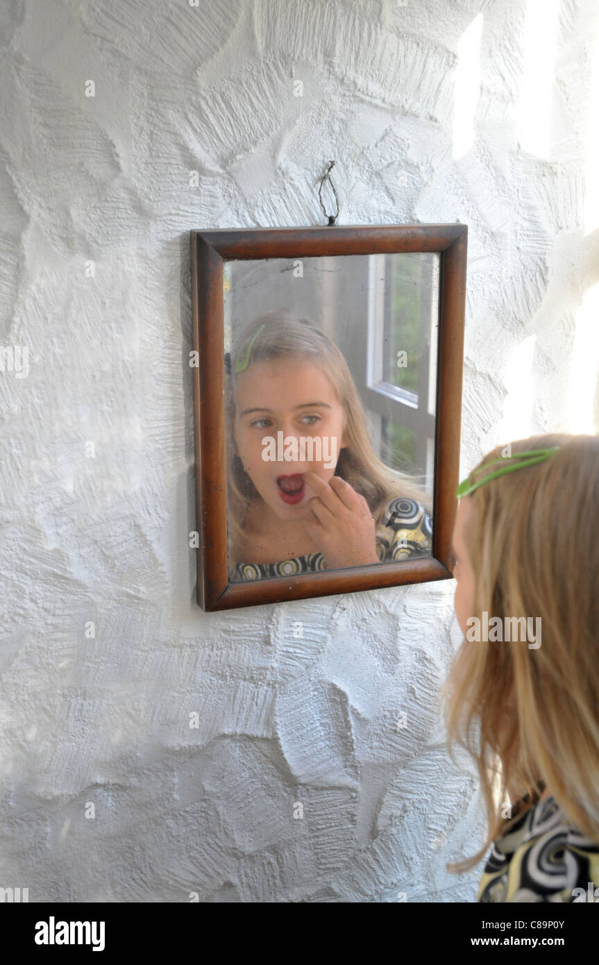 Une fille de 8 ans, appliquer le rouge à lèvres pratiques dans le miroir Banque D'Images