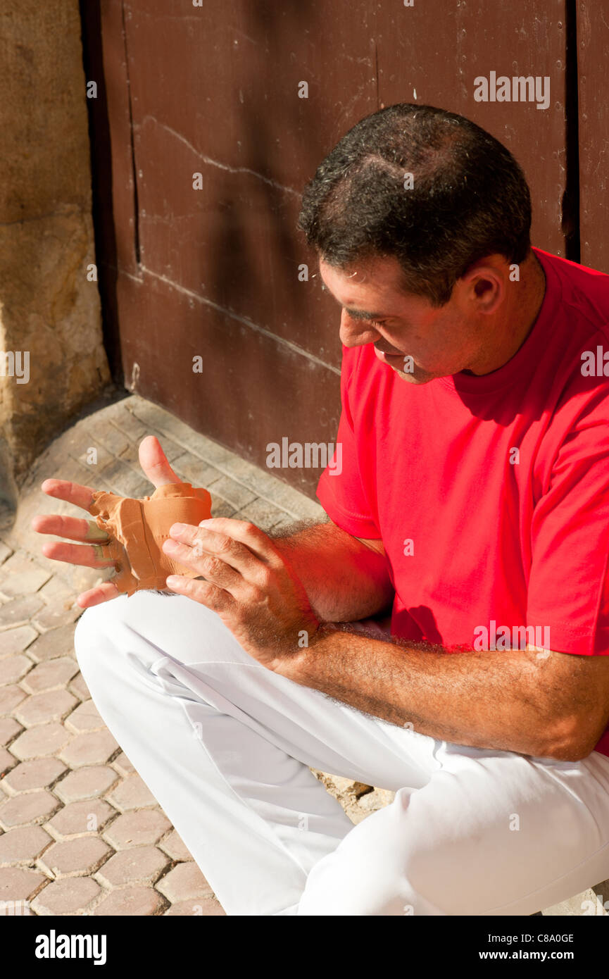 Joueur de pelote basque espagnol traditionnel rituellement enroulant ses doigts dans les protections de plâtre Banque D'Images