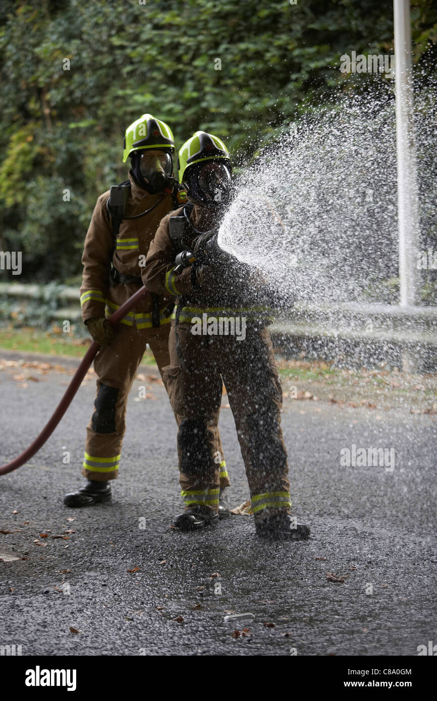 Les pompiers avec un flexible portant des appareils respiratoires, UK Banque D'Images