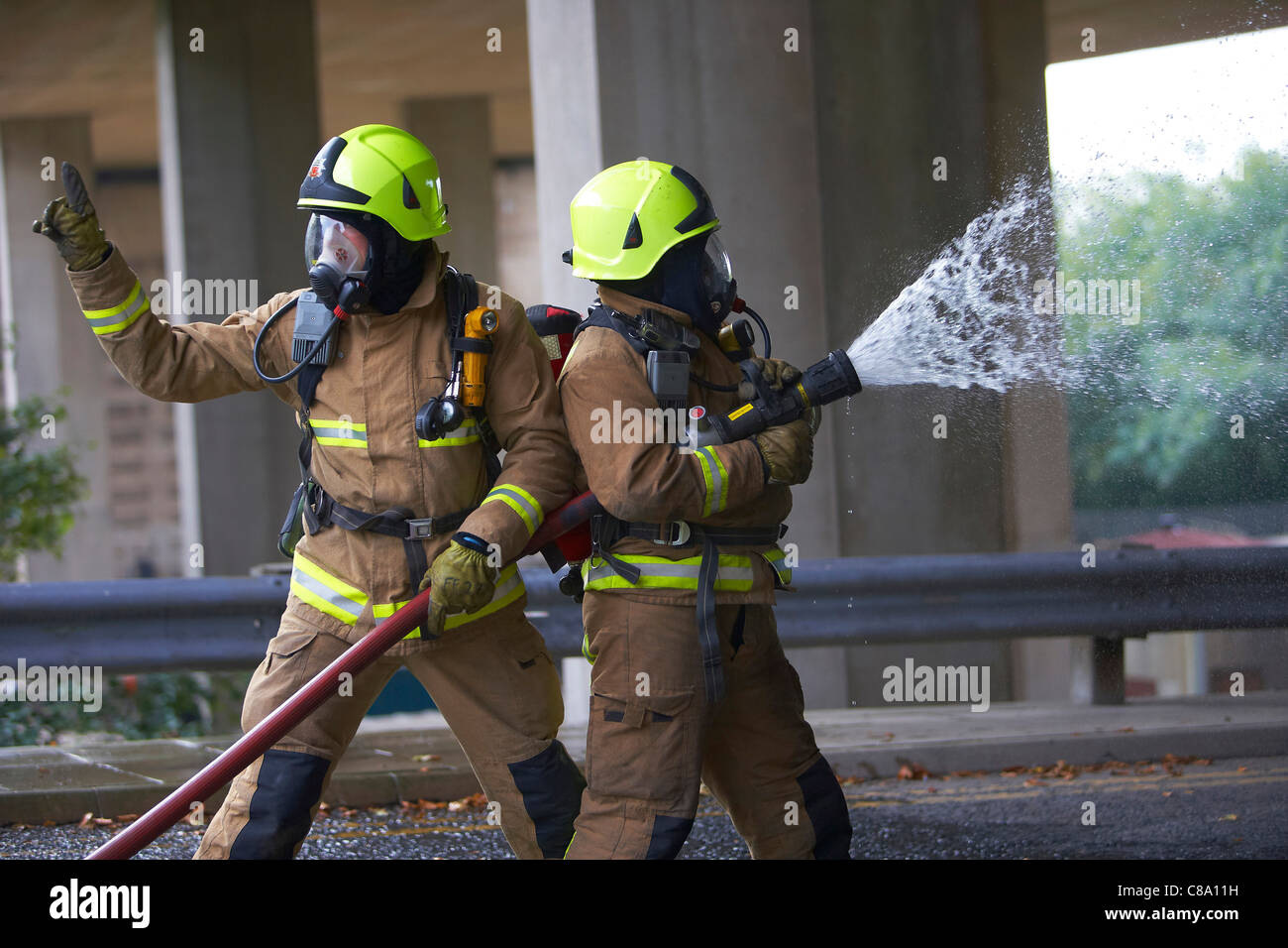 Les pompiers avec un flexible portant des appareils respiratoires, UK Banque D'Images