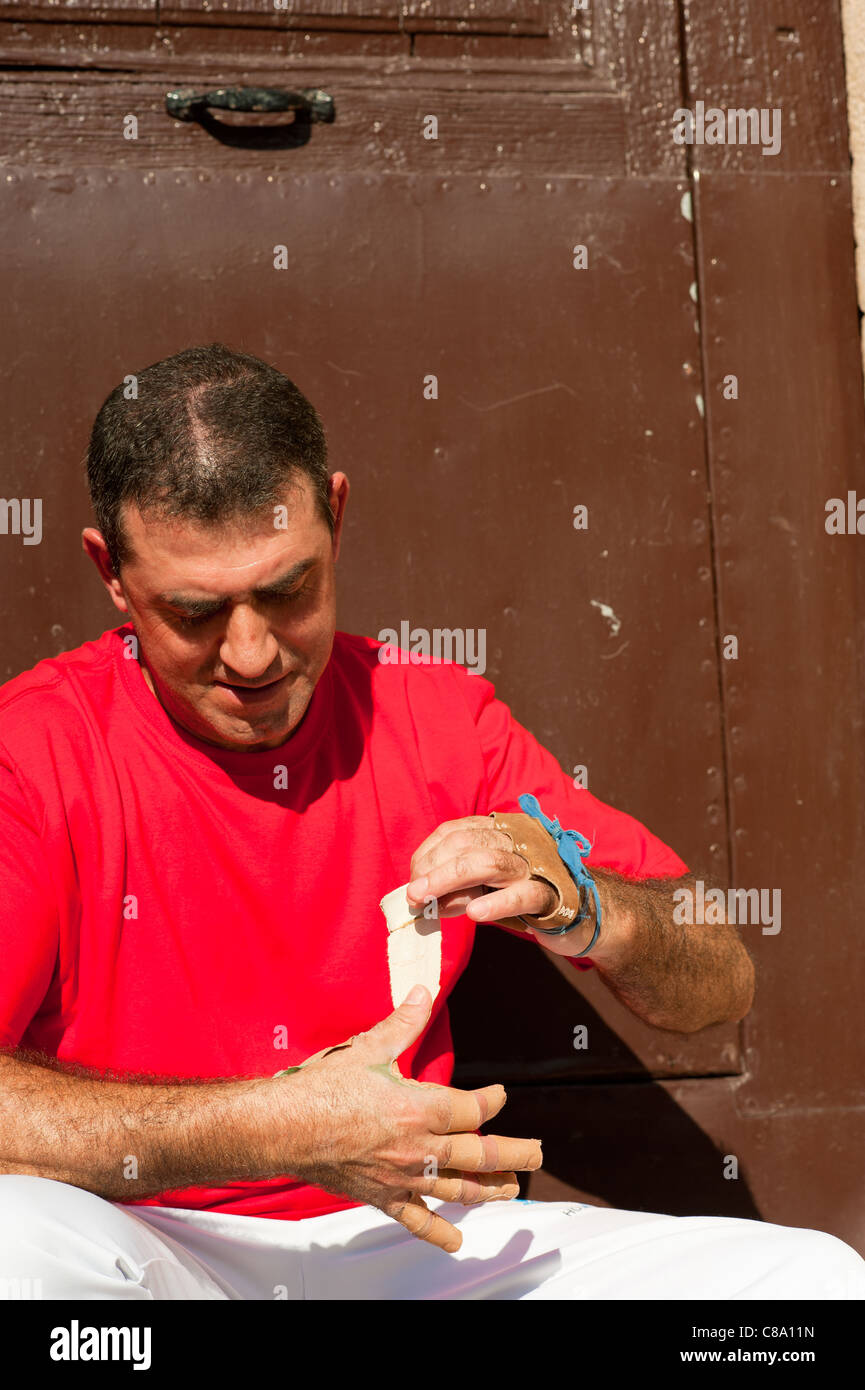 Joueur de pelote basque espagnol traditionnel rituellement enroulant ses doigts dans les protections de plâtre Banque D'Images