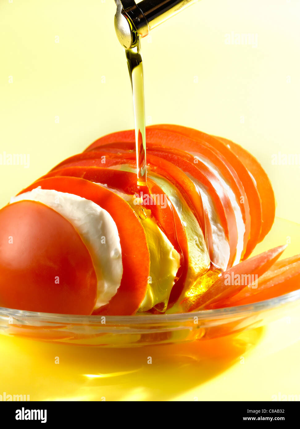 Verser l'huile d'olive sur un plat de tomates et mozzarella Banque D'Images