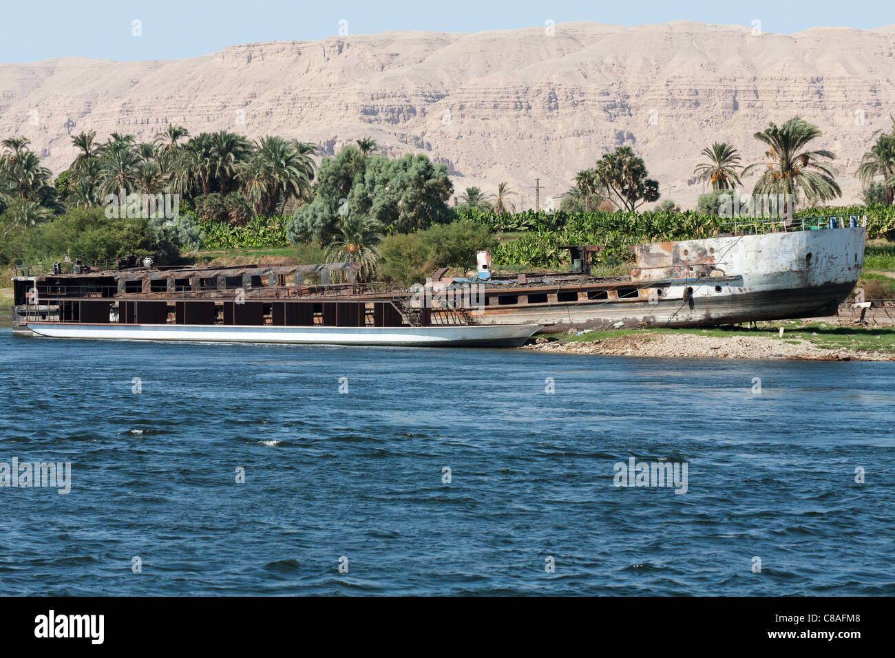 L'article de Nil banque avec coque de rouille d'un grand bateau avec cadre métallique d'un moderne dahabiya amarrés devant, Egypte Banque D'Images