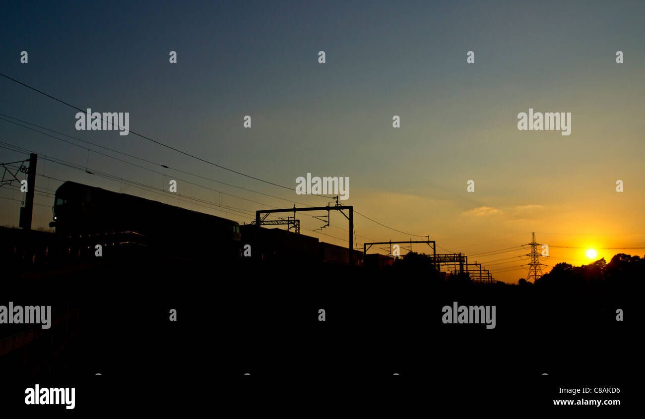 Classe 66 intermodal Freightliner et train, silhouetté passant Huddlesford près de Lichfield, dans le Staffordshire, en Angleterre. Banque D'Images