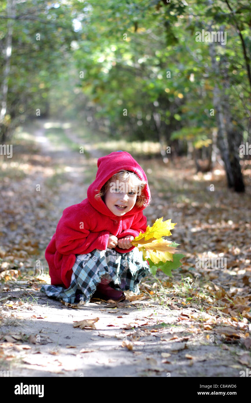 La petite fille dans une tête rouge dans la forêt d'automne Banque D'Images