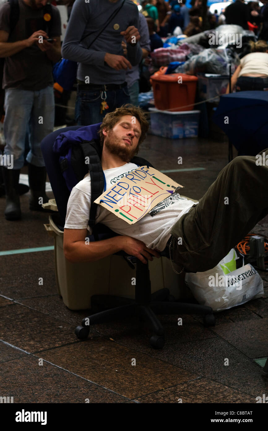 Occupy Wall Street manifestant nommé Luc se reposant dans une chaise de bureau à l'intérieur de Zuccotti Park à New York. Banque D'Images
