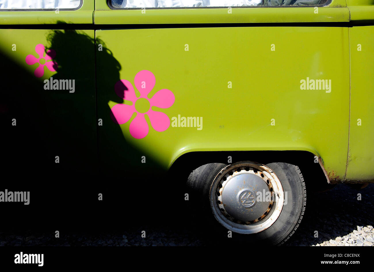 © Tony Barthélemy l'ombre d'un garçon comme il passe par un camping-car Volkswagen classique avec des fleurs roses. Banque D'Images