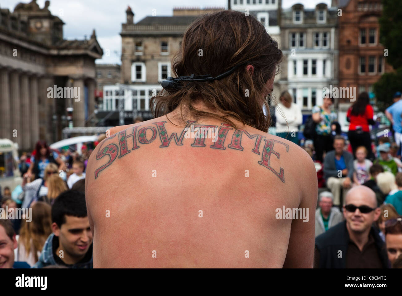 Artiste de rue à l'Edinburgh Fringe Festival avec un tatouage de 'Showtime' sur le dos, jouant à un public sur la Butte Banque D'Images