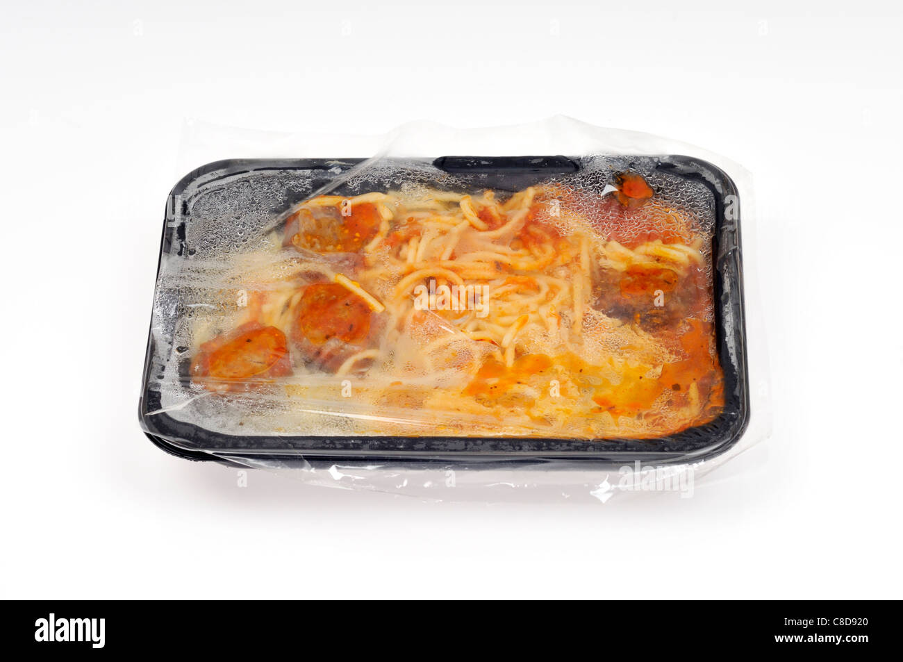 Le bac d'un four micro-ondes, cuit et chaud spaghetti et boulettes de viande prêt repas avec plateau en plastique & film couvrir sur fond blanc. Banque D'Images